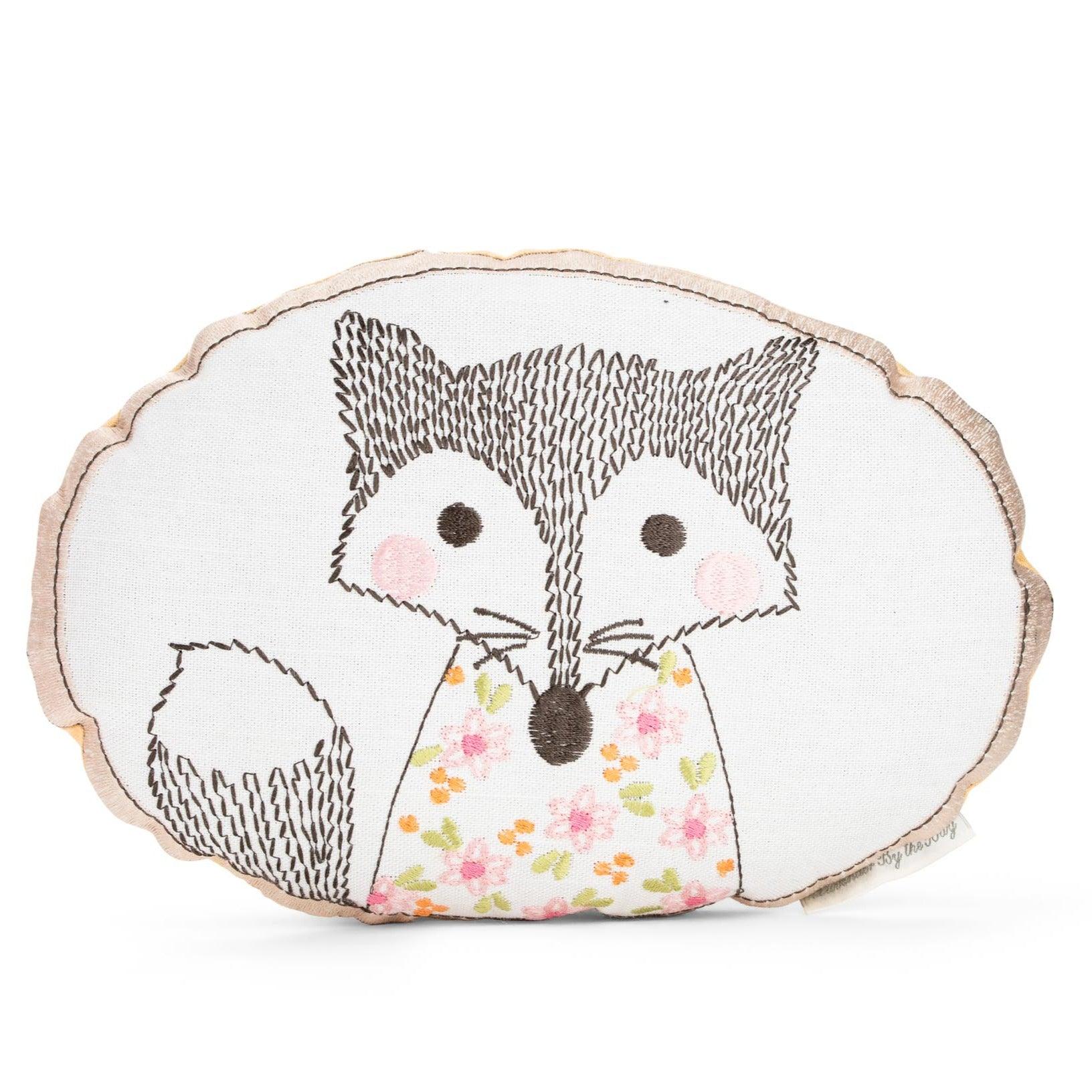 A soft, oval-shaped lavender sachet with an embroidered Fantastic Mr. Fox design. The fox has a fluffy tail and is wearing a floral dress.