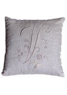 A square, off-white monogrammed cushion with the letter "V." Delicate floral patterns and swirling flourishes dance around the initial, creating a captivating design. The pillow's soft texture and subtle sheen exude a sense of luxury and elegance, making it a timeless addition to any décor.