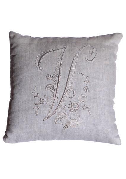 A square, off-white monogrammed cushion with the letter "V." Delicate floral patterns and swirling flourishes dance around the initial, creating a captivating design. The pillow's soft texture and subtle sheen exude a sense of luxury and elegance, making it a timeless addition to any décor.