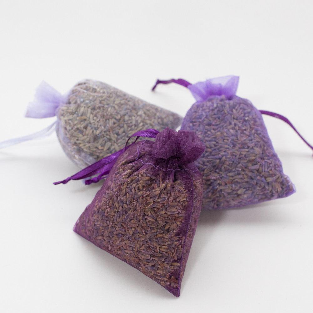 Three purple lavender sachets for drawers tied with a purple ribbon on white background