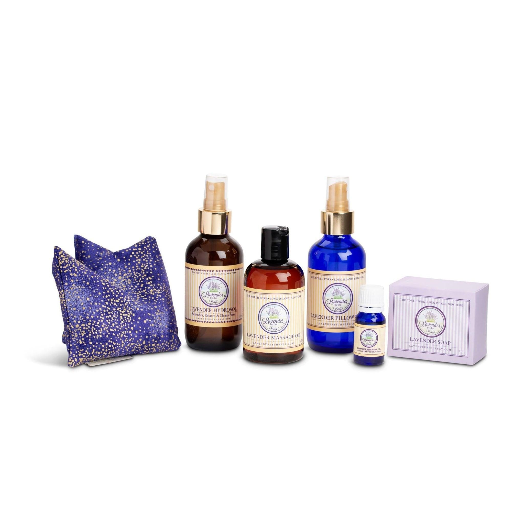 the products of the Spa gift set - lavender hydrosol, lavender pillow mist, lavender essential oil, lavender massage oil in a glass bottle with a dropper top, lavender bar soap, and a lavender eye pillow on white background