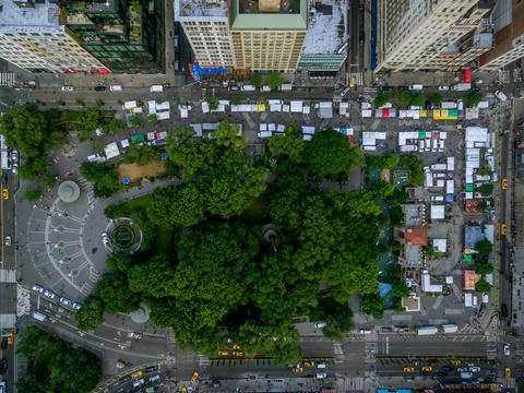 union square greenmarket photo from above showing a sqaure wtih stands and bunch of trees in the middle alongside high building towers