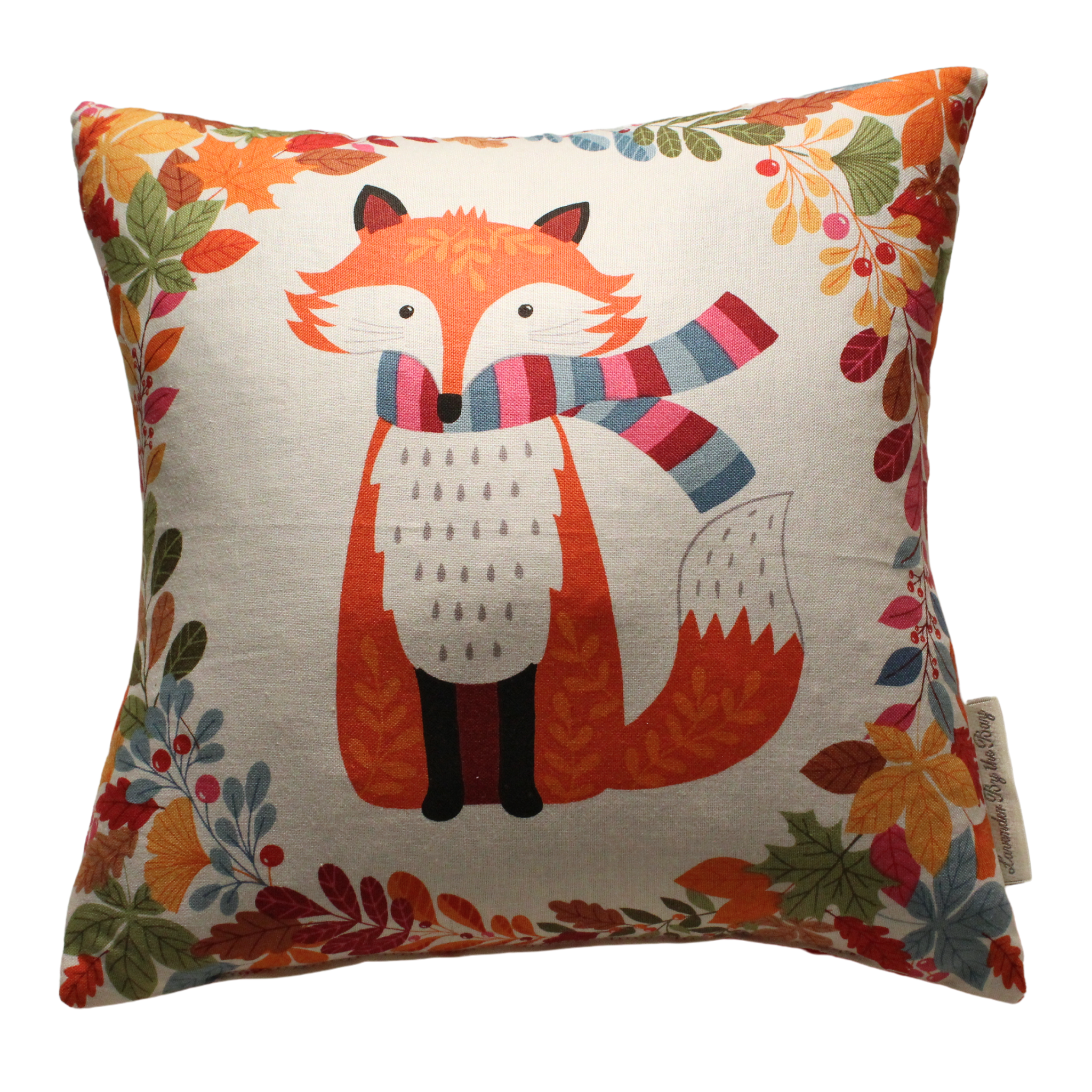 A square pillow with a cream-colored background features a cartoon fox wearing a colorful scarf. The fox is standing in the center of the pillow, surrounded by a border of autumn leaves and berries.